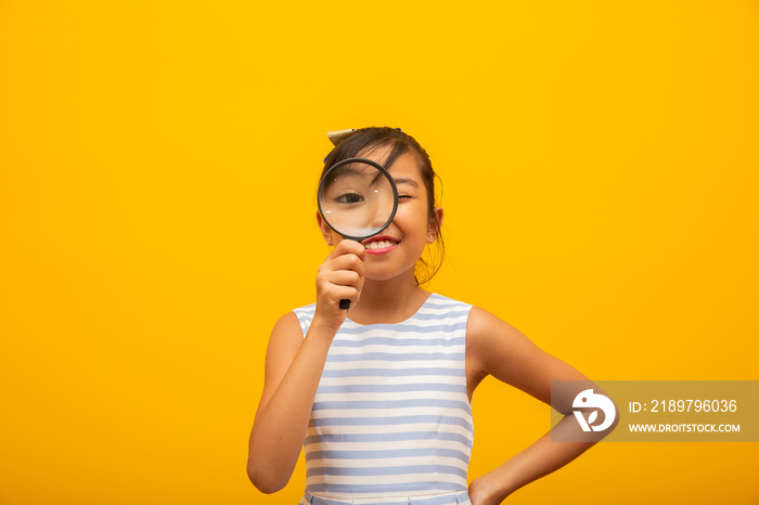 Portrait of happy little Asian child with magnifying glass.