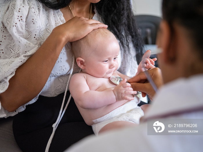 Nurse examining baby girl (2-5�months)�with stethoscope