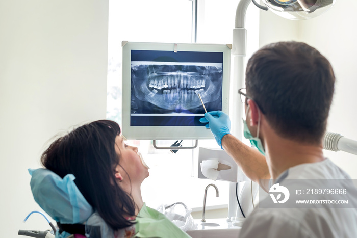 Doctor dentist pointing on patients X-ray on monitor