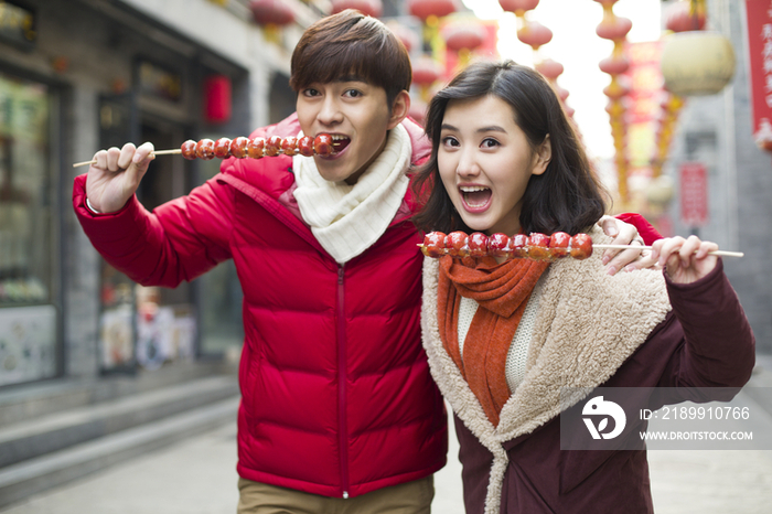 年轻情侣逛街吃冰糖葫芦
