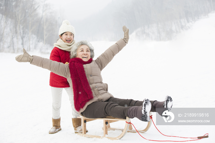 奶奶和孙女在雪地上玩雪橇