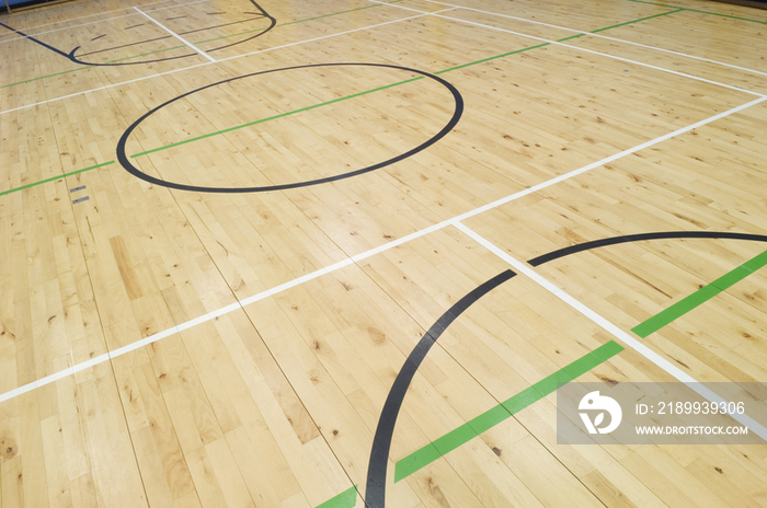 Court markings on the wooden floor of the sports hall of a modern secondary school