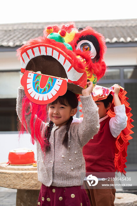 快乐的兄妹俩在院子里舞狮子