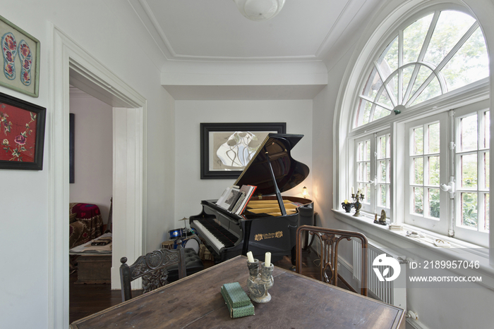 Piano by arched French windows with cropped table in foreground