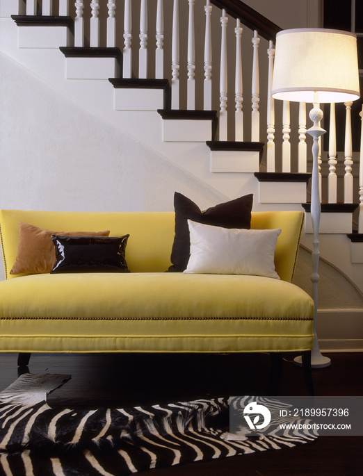 Yellow sofa and floor lamp by staircase in house