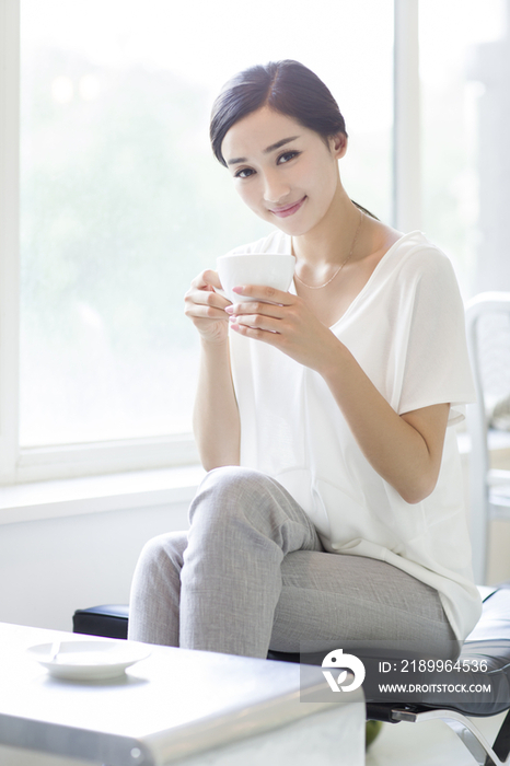 快乐的年轻女子在咖啡店喝咖啡