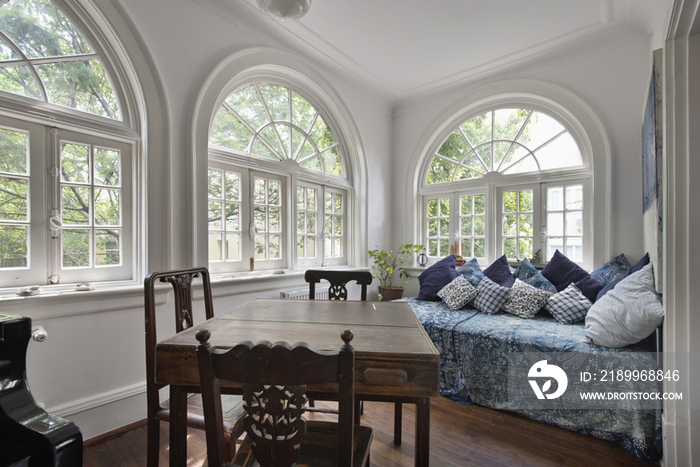 Large windows with chairs around wooden table in foreground at bedroom