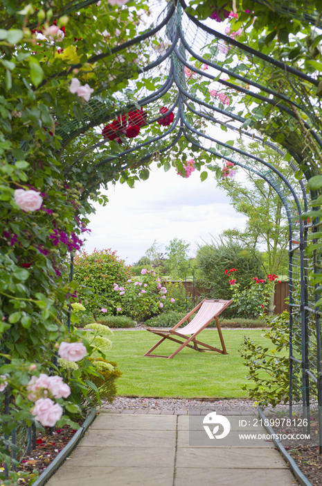 A garden with a rose arch, and a deck chair