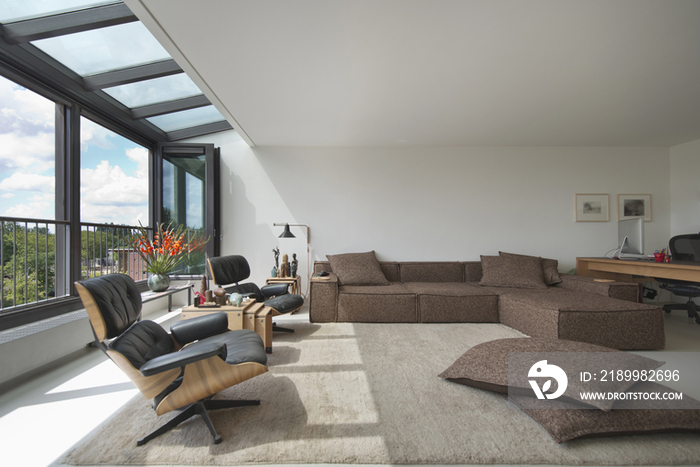 Large living room with rug on floor and view of trees through window