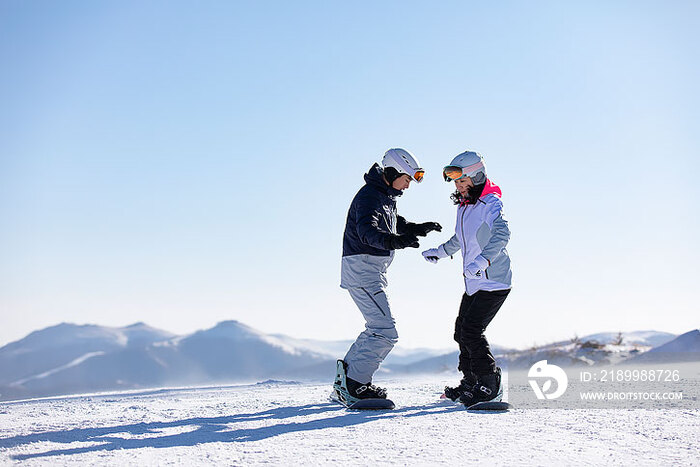 年轻男子教女朋友单板滑雪