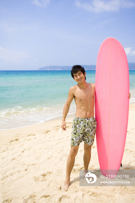 男孩在沙滩上拿着冲浪板