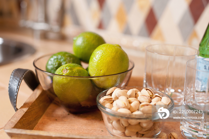 Close-up of oranges and pistachios in bowls against blurred backsplash on kitchen counter