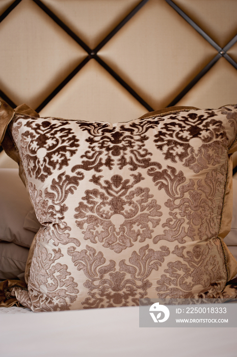 Extreme close-up of designed throw pillow on bed against headboard