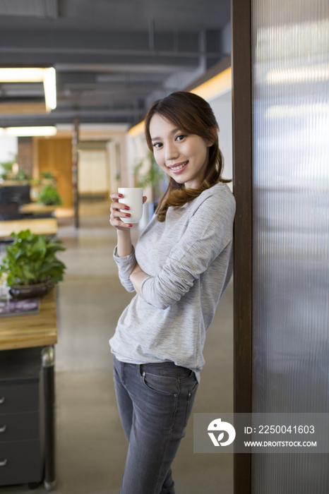 年轻女子在办公室喝咖啡