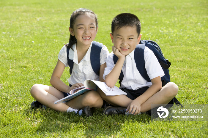 两个在草地上看书的小学生