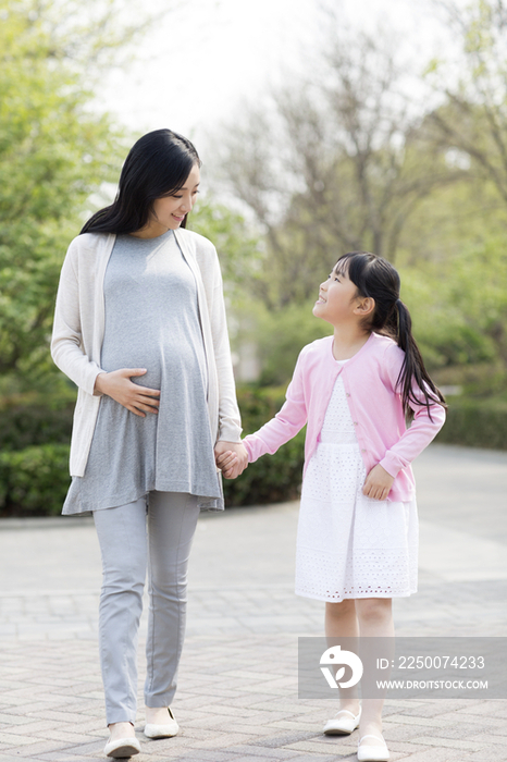 怀有身孕的妈妈和女儿手牵手散步