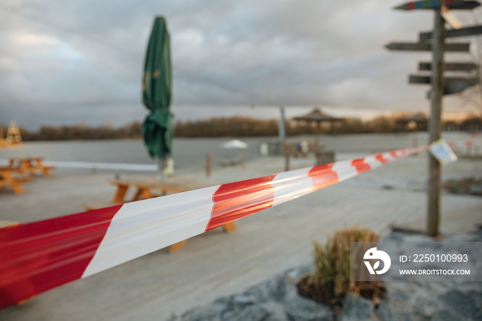 Locked beach on a lake in Germany. Sandy beach with chairs and a barrier tape. red and white striped