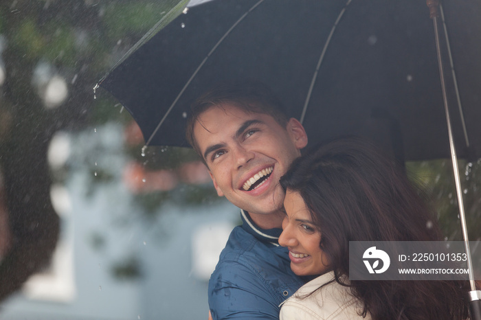 幸福的年轻情侣雨中撑伞