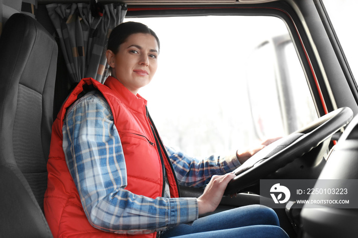 Young female driver sitting in cabin of big modern truck