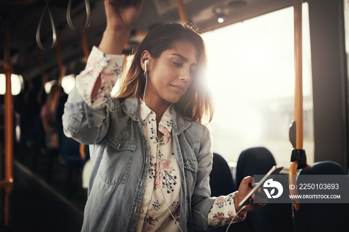 年轻女子站在公交车上听音乐