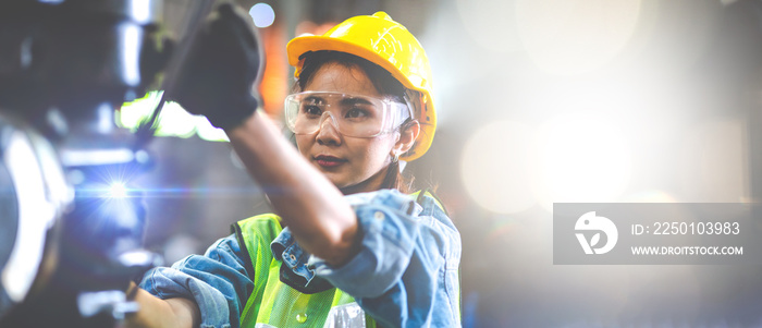 Woman worker wearing safety goggles control lathe machine to drill components. Metal lathe industria