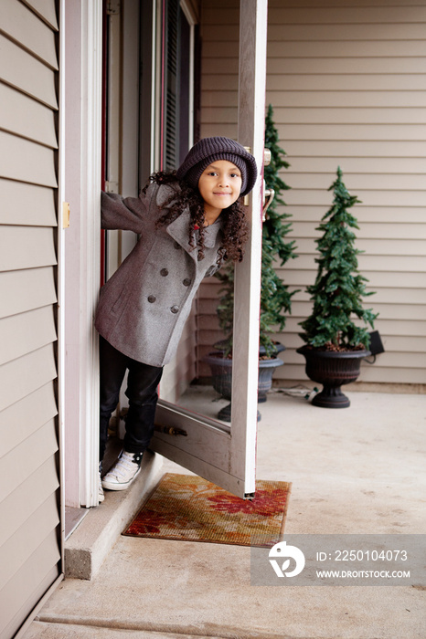 Girl (6-7) leaning out front door