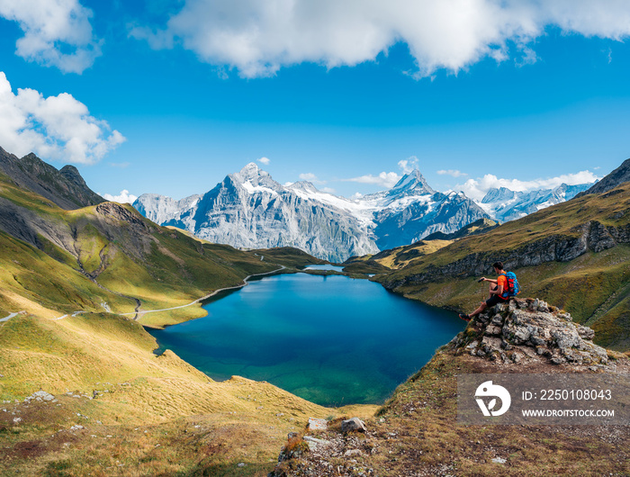 Enjoy the amazing view from top of the world. Hiker watching reflection of mountains at Bachalpsee l