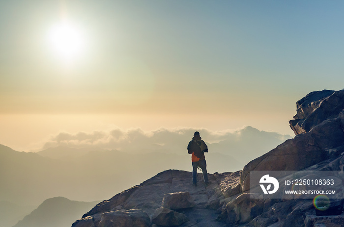 一个人站在摩西山的悬崖边上，看着埃吉普山脉的日出