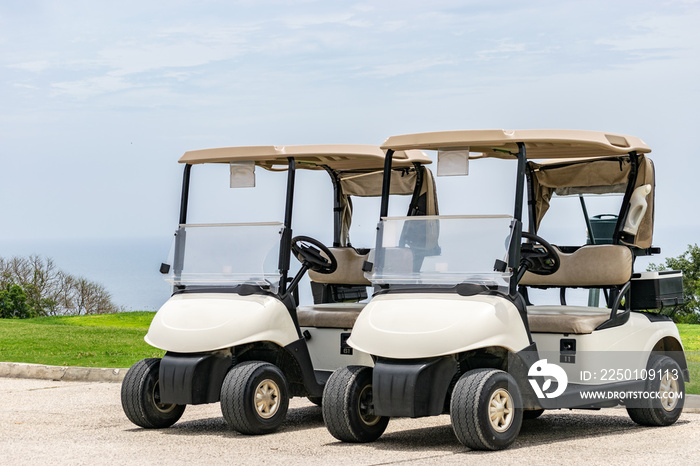 Two empty white golf carts parked beside each other on the driveway of a golf course in Montego Bay,