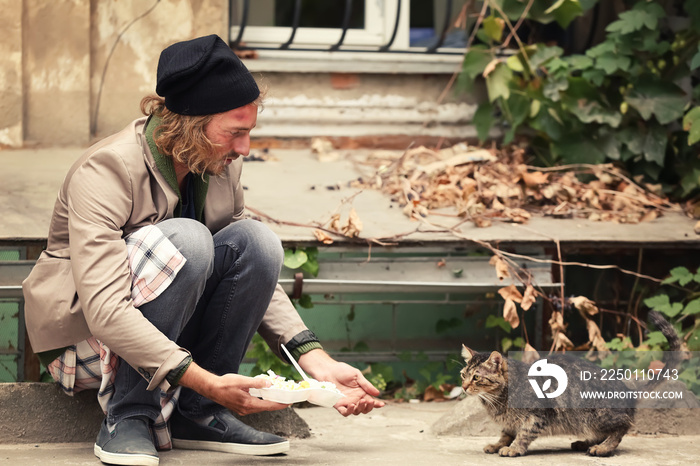 Poor man sharing food with homeless cat outdoors