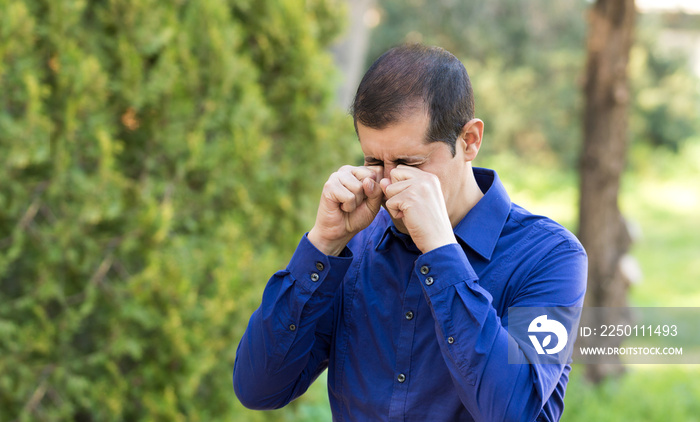 Disgusted man rubbing his eyes in a nature