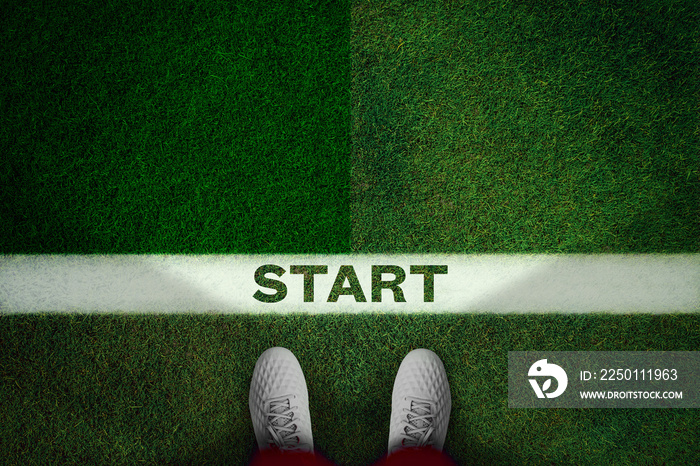 Top view of white soccer boots on green field whith text START.