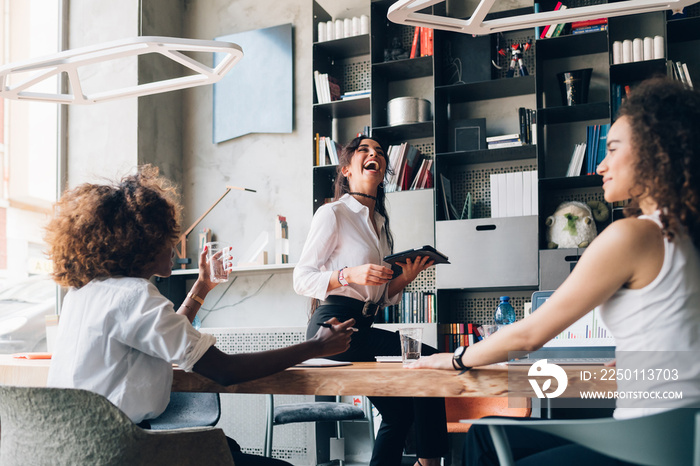 three young multicultural businesswomen having informal meeting in modern office