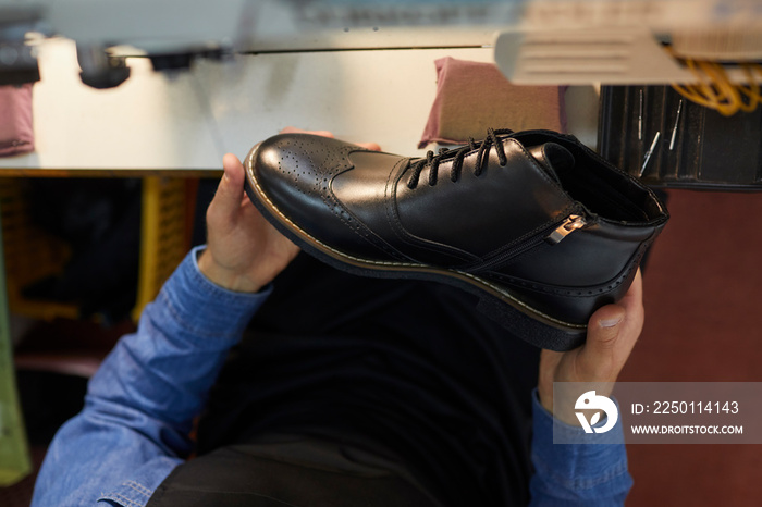 一名男子拿着黑色皮靴。从鞋法手中的新款时尚鞋的上方特写