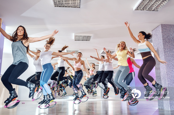 一群健康快乐的年轻女性穿着袋鼠鞋在健身工作室跳跃。