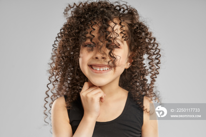 Little smiling girl with curly hair on face.