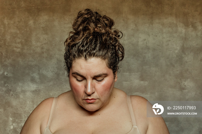 close up portrait of a plus size woman facing forward head down eyes closed curly hair