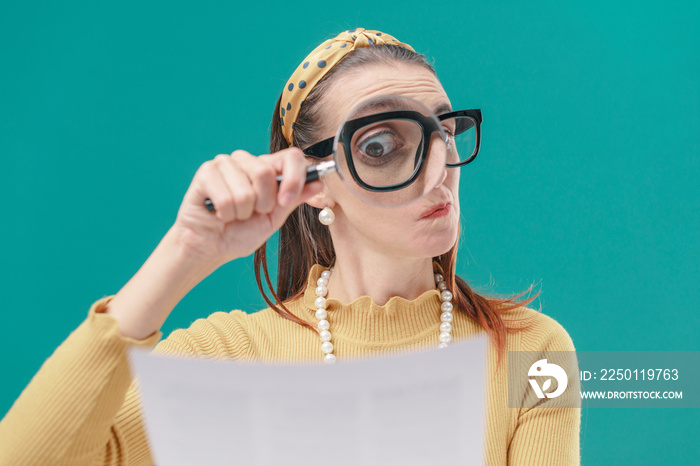 Woman checking carefully a document using a magnifier