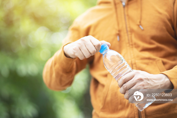 close up Sport man hand holding fresh drinking water from bottle while exercising in the park.