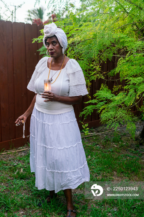 花园里的女人用蜡烛和念珠祈祷