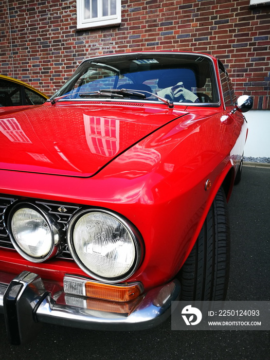 Rotes italienisches Coupé der Siebzigerjahre mit Doppelscheinwerfer beim Oldtimertreffen im Lenkwerk