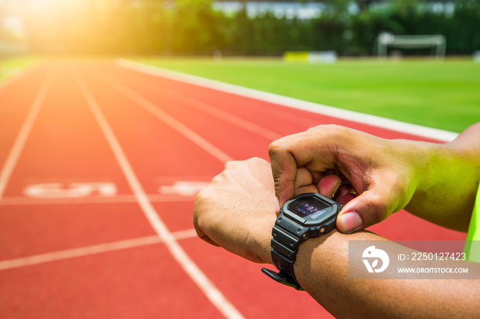 Athlete checking his watch on running track