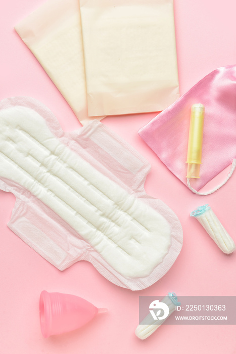 Menstrual cup, pads and tampons on pink background