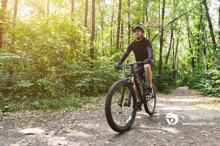 Cycler在阳光下骑行在森林小径上