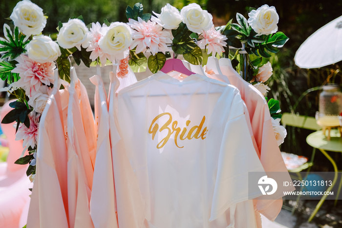 Beautiful white bathrobes for the bride and her bridesmaids hanging in the yard at a bachelorette pa