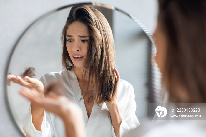 Hairloss Concept. Worried Young Woman Holding Bunch Of Fallen Hair In Hand