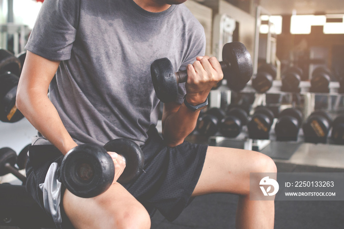 Closeup of a thin man doing exercises with dumbbell. Fitness muscular body. Fitness concept