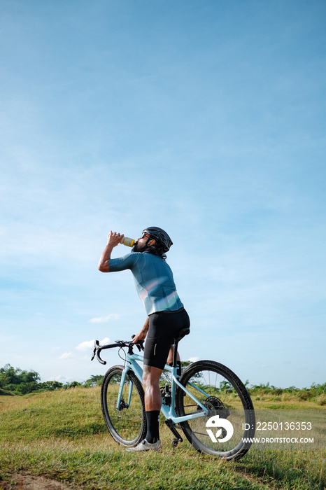 A young bearded cyclist is biking through a field