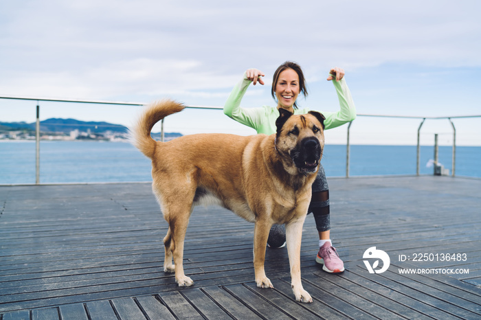 Portrait of cheerful female trainer enjoying leisure time with lovely purebred dog having fun at boa