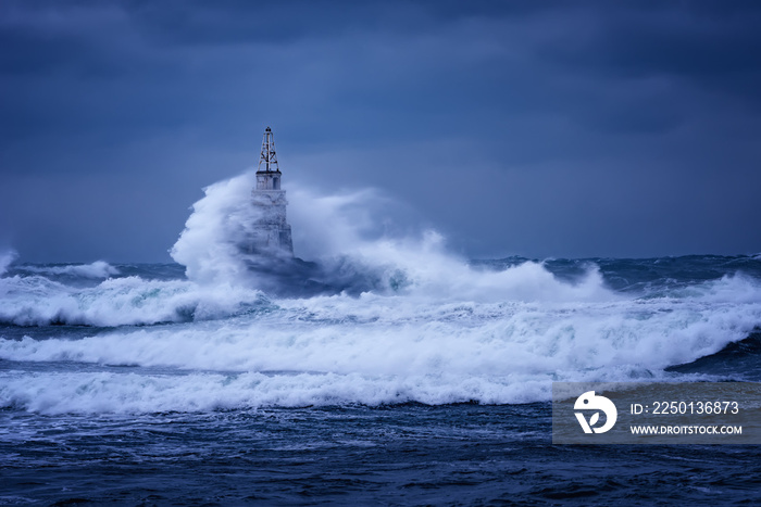 Big wave against old Lighthouse in the port of Ahtopol, Black Sea, Bulgaria on a moody stormy day. D